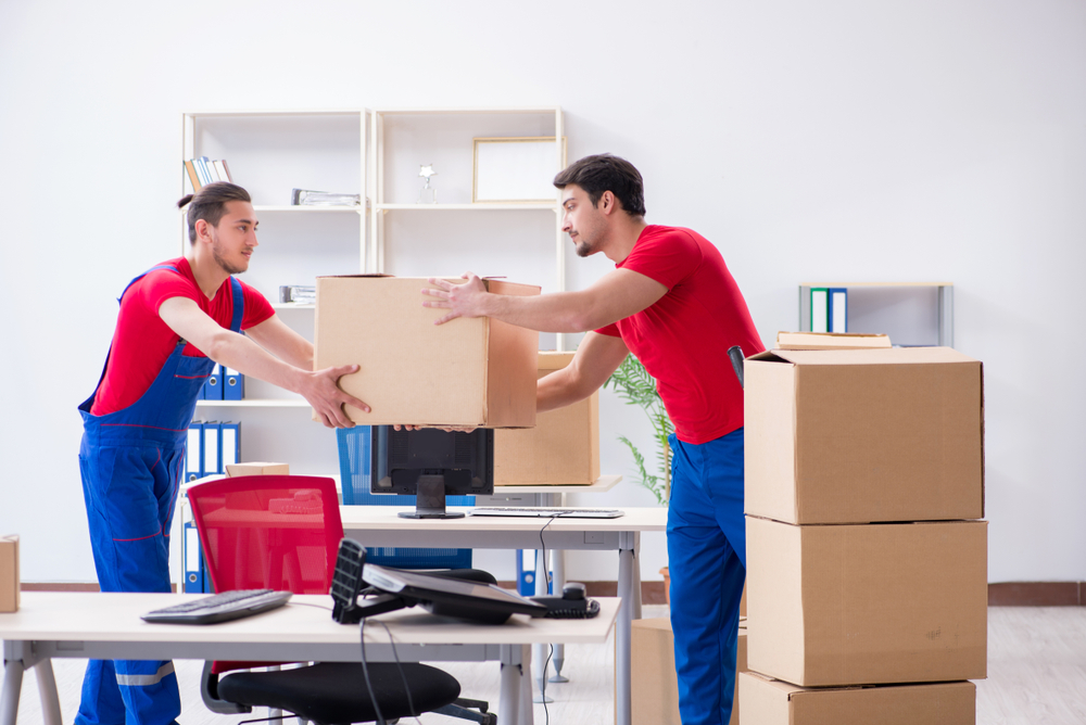 Movers from one of the Mississauga moving companies passing a box to each other while conducting commercial moving.